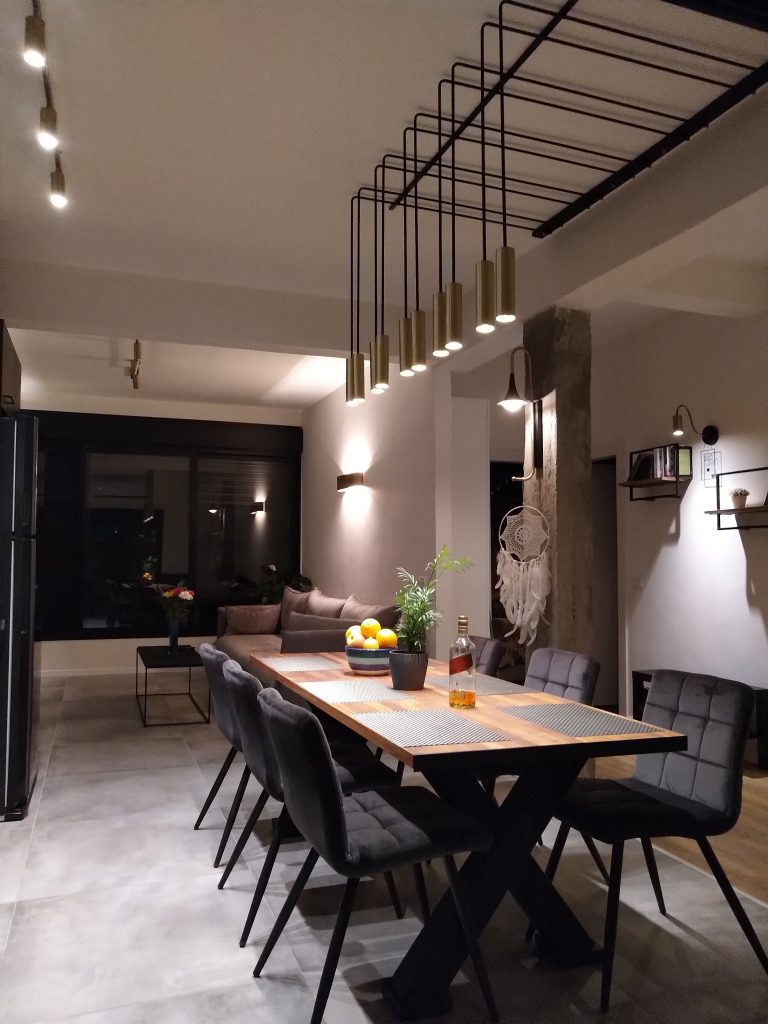 גוף תאורה שחור מוארך עם נורות תלויות מעל שולחן אוכל